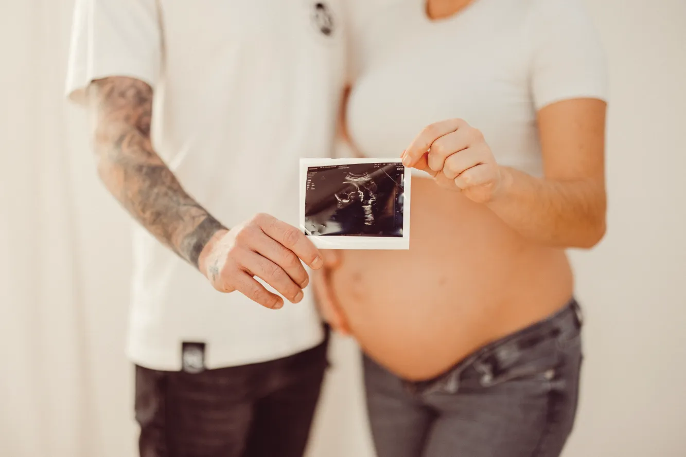Ein Junges Päärchen zeigt stolz ein Ultraschall Foto Ihres Babys. 